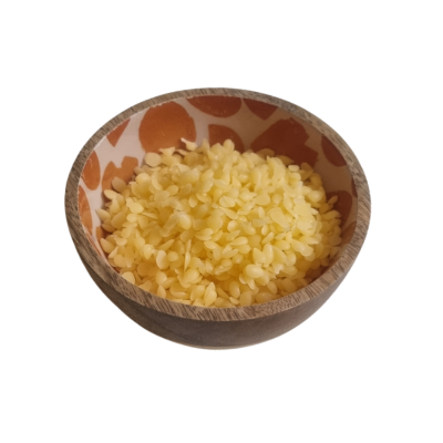 A wooden bowl with ceramic pattern edge containing beeswax pellets to illustrate one of the 4 ingredients in Scrummy Cream 