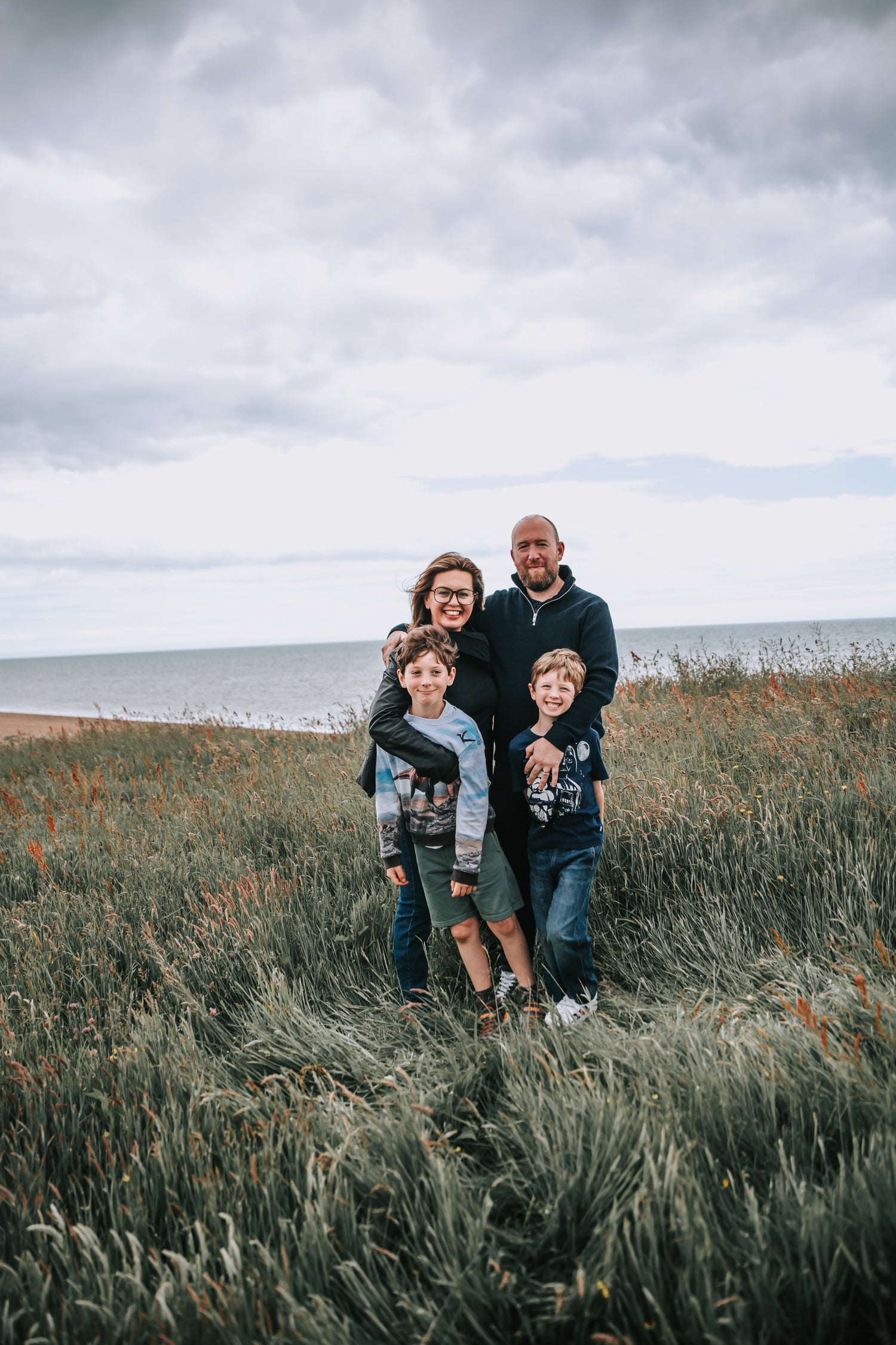 Mr and Mrs Bailey standing with their two children in some long grass by the beach